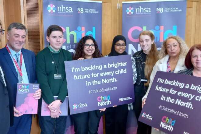 Event attendees hold up pledge cards to show their support for children in the North